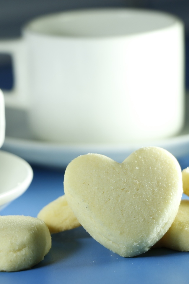 Сладкое печенье в форме сердца с кружками на столе