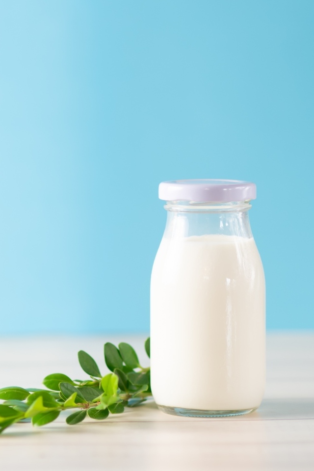 Бутылка молока с листьями на голубом фоне