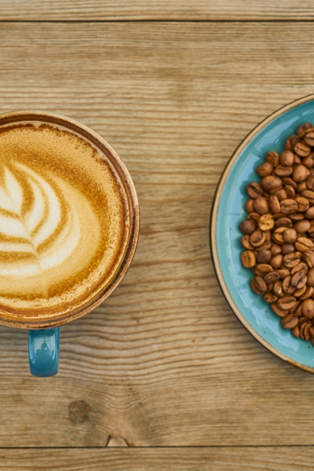 Чашка кофе с рисунком на столе с зернами