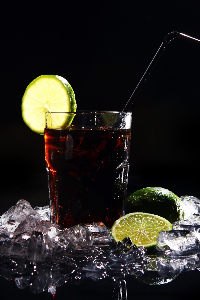 Стакан колы со льдом на черном фоне с кусочками лимона