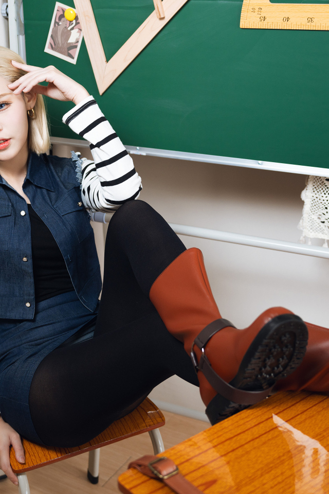 Девушка азиатка в сапогах сидит за столом в школе