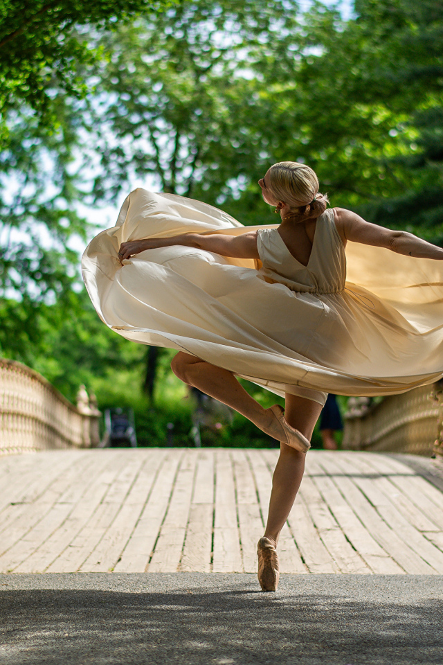 Девушка балерина в стойке на мосту