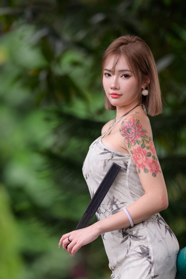 Красивая девушка азиатка с татуировкой на руке