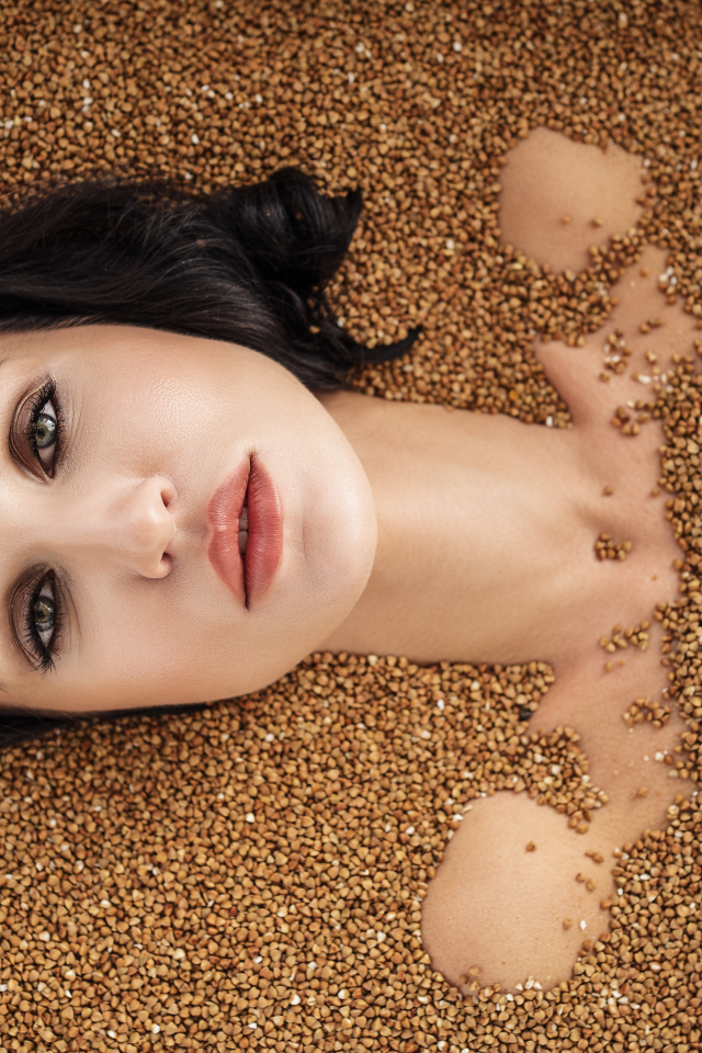 Красивая девушка лежит в зернах гречки