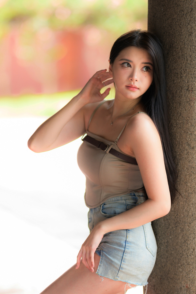 Милая длинноволосая азиатка стоит у колонны