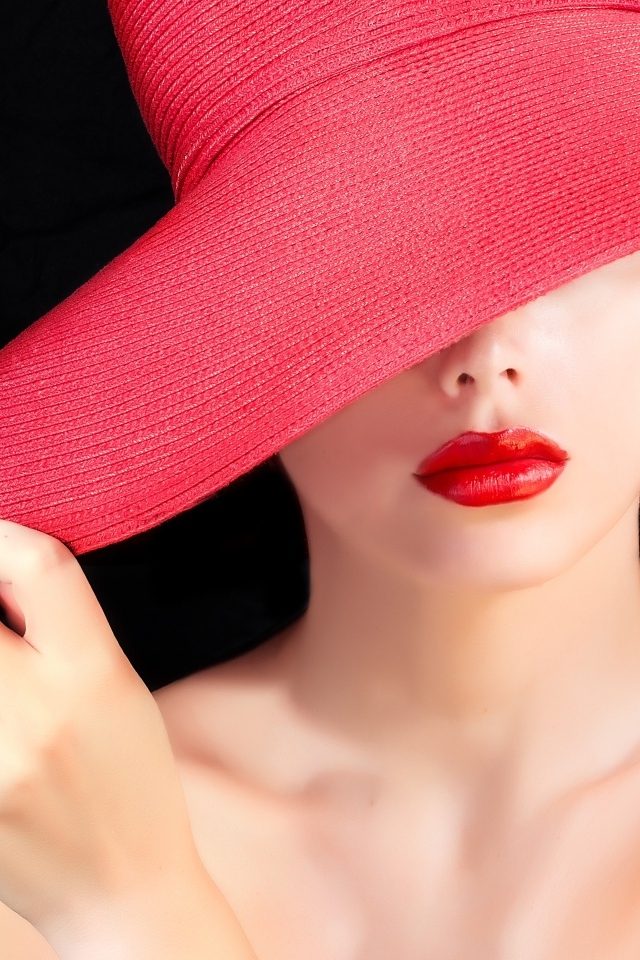 Девушка в большой красной шляпе на черном фоне