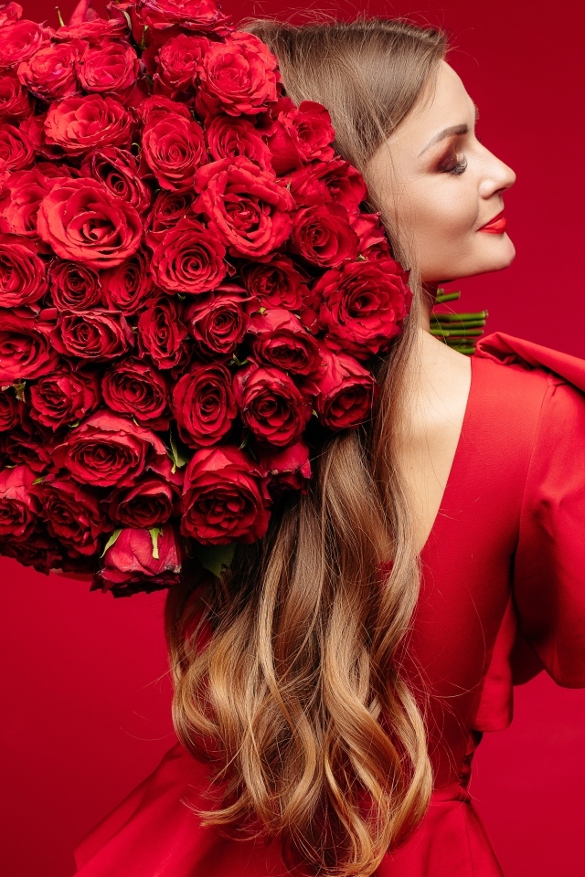 Девушка в красном платье с большим букетом роз
