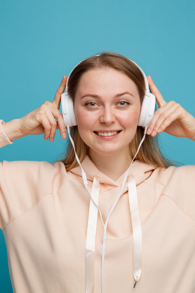 Улыбающаяся девушка в наушниках на голубом фоне