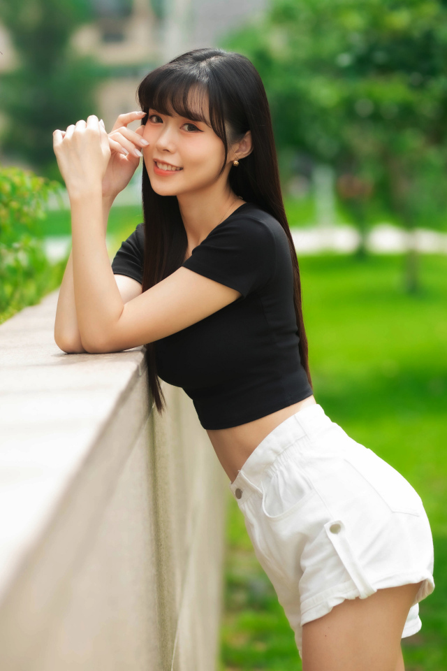 Молодая азиатка в белых шортах и футболке