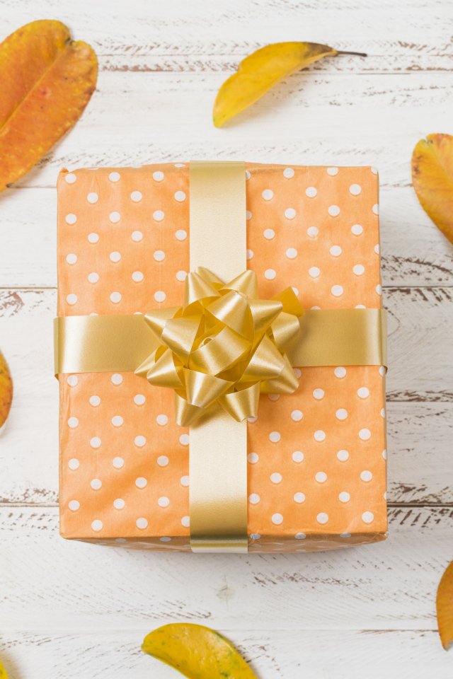 Подарок с желтыми листьями на белом фоне