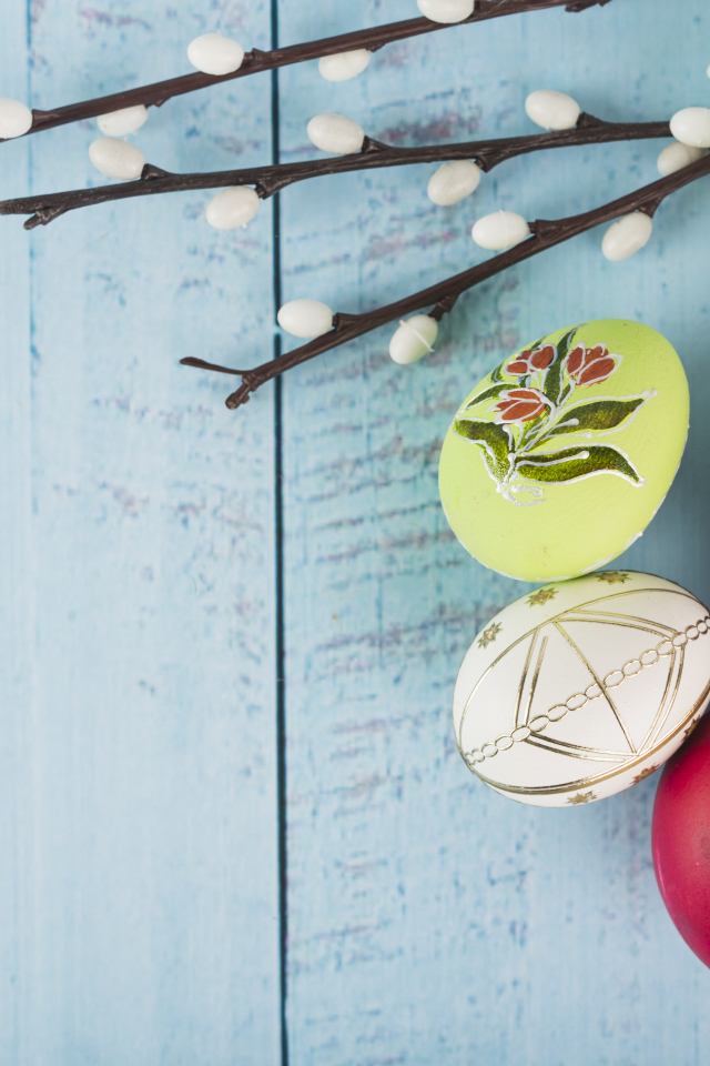 Красивые пасхальные яйца с ветками вербы и цветами хризантемы на голубом фоне