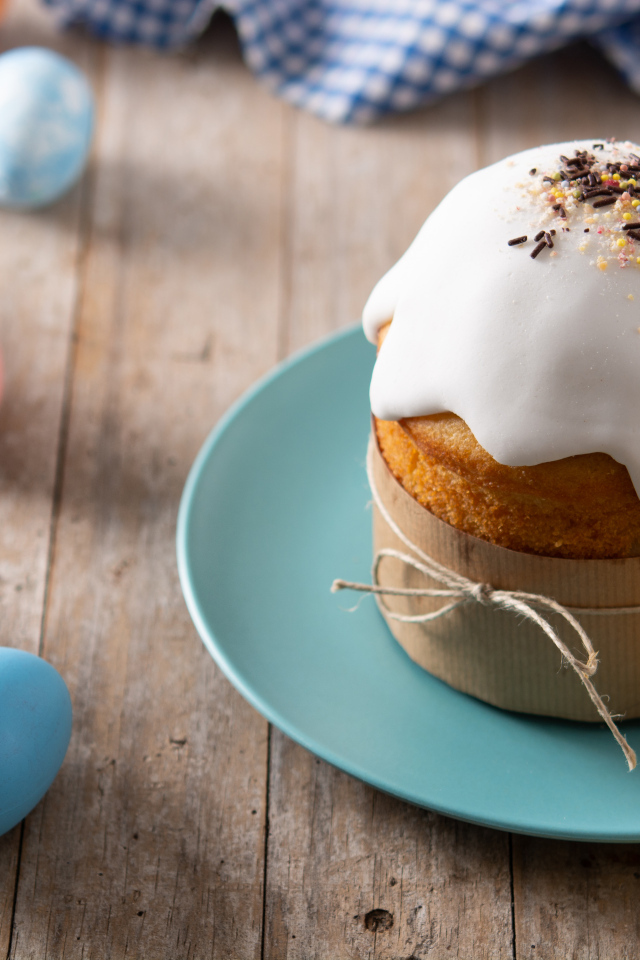 Кулич с крашеными яйцами и цветами на столе на Пасху