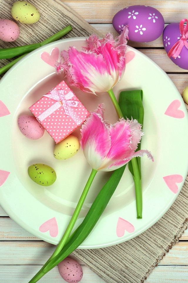 Пасхальные яйца с тюльпанами на тарелке на столе