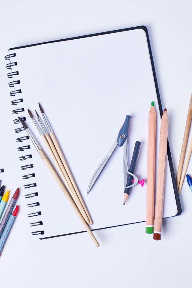 Карандаши, кисти и блокнот для рисования на сером фоне