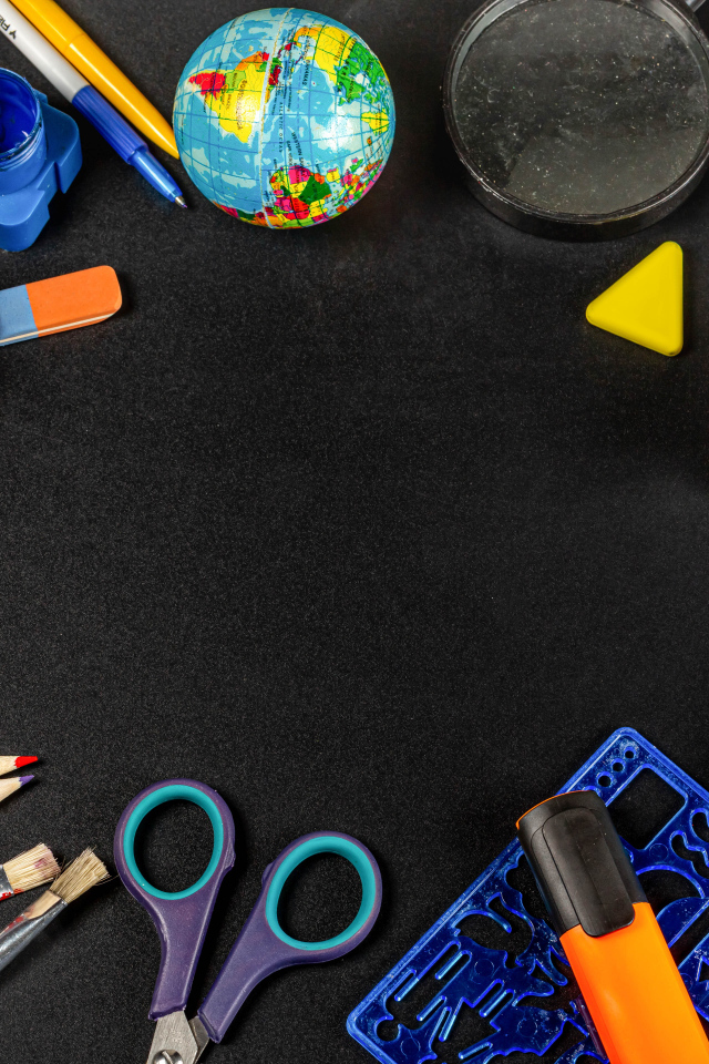 Канцелярские предметы, глобус и игрушечный автобус на черном фоне