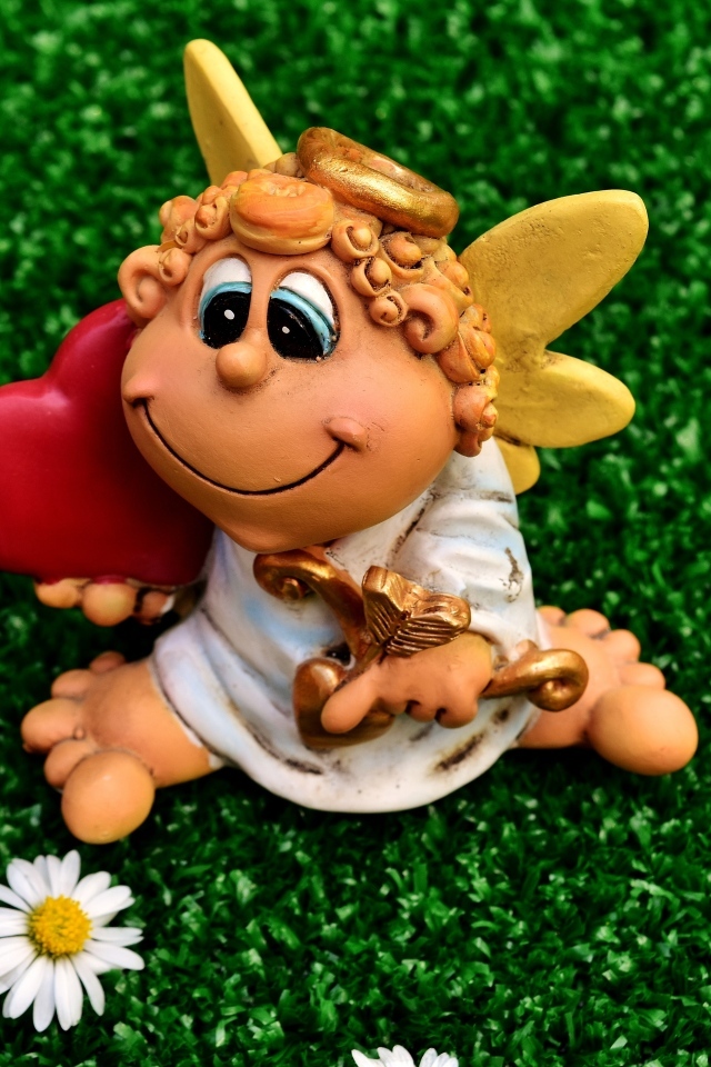 Статуэтка ангела на зеленой траве с белыми ромашками