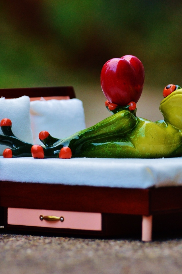 Фигурка зеленая лягушка с красным сердцем на кровати