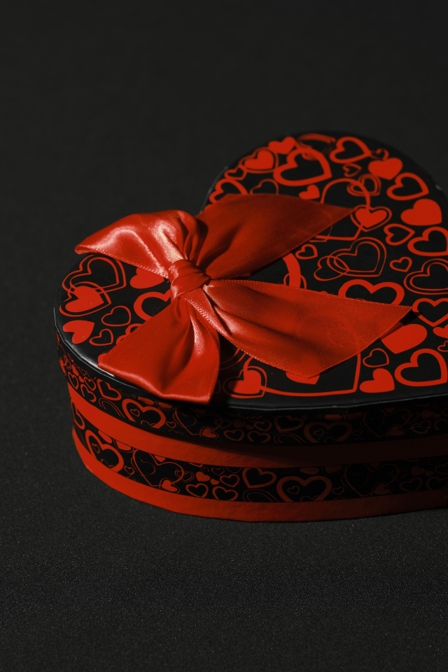 Шкатулка в форме сердца с красным бантом на черном фоне