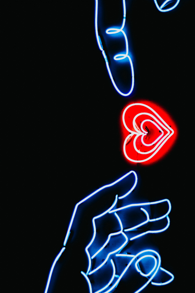 Неоновое красное сердце с руками на черном фоне
