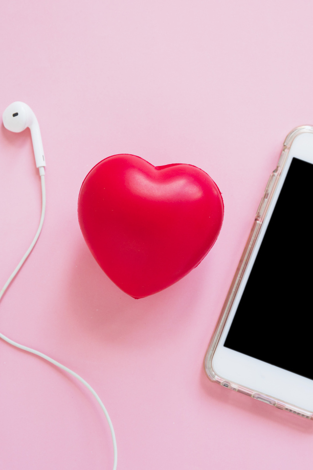 Телефон, наушники и красное сердце на розовом фоне