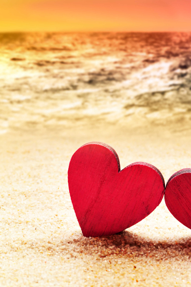 Два красных сердечка на песке на пляже