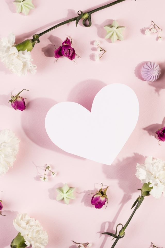 Белое бумажное сердце на розовом фоне с цветами