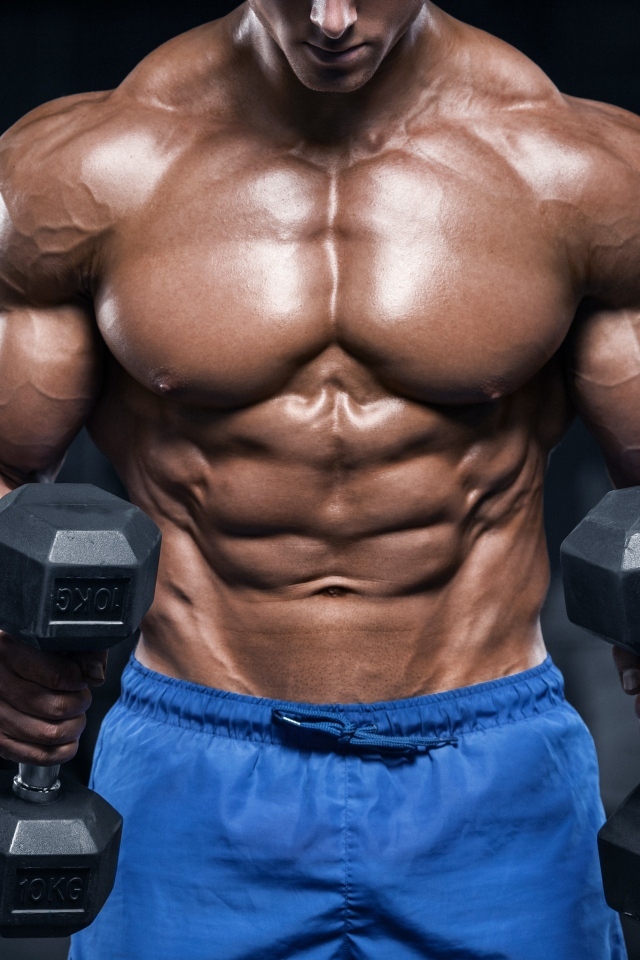 Накаченное тело мужчины с гантелями в руках