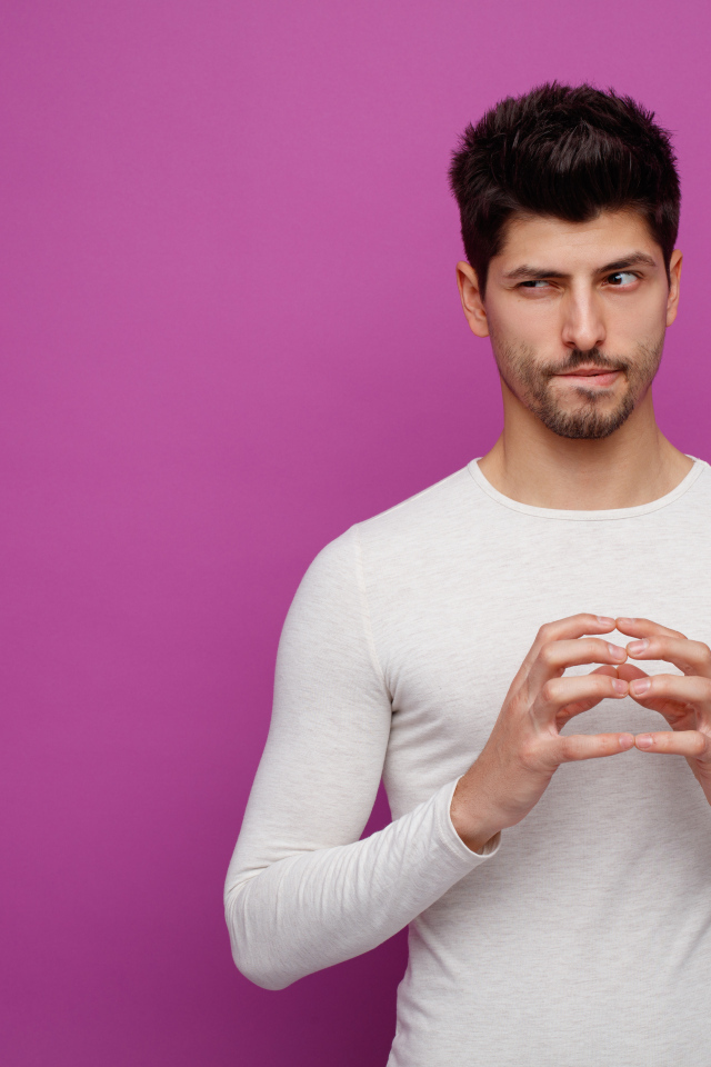 Хитрый мужчина в белом свитере на сиреневом фоне