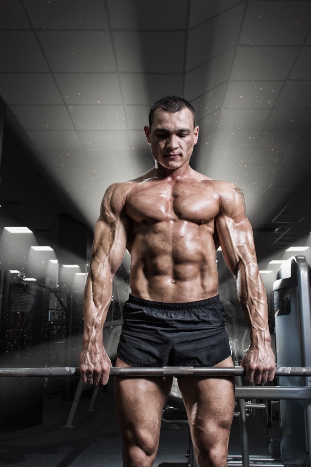 Сильный мужчина качает штангу в спортзале