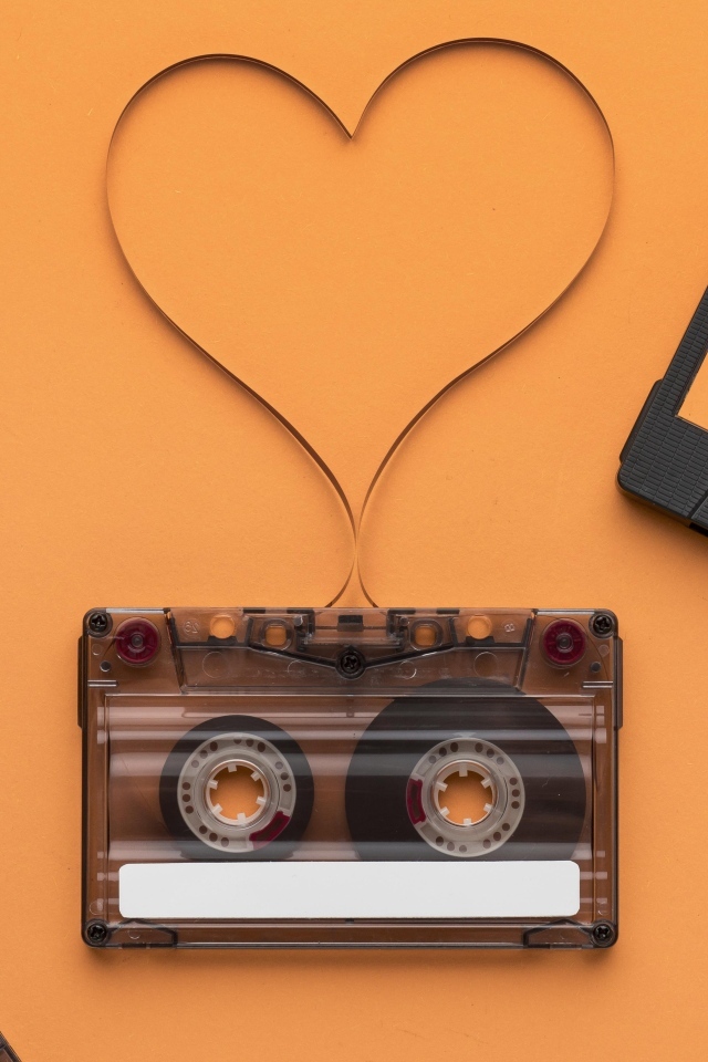 Кассеты и сердце из ленты на оранжевом фоне