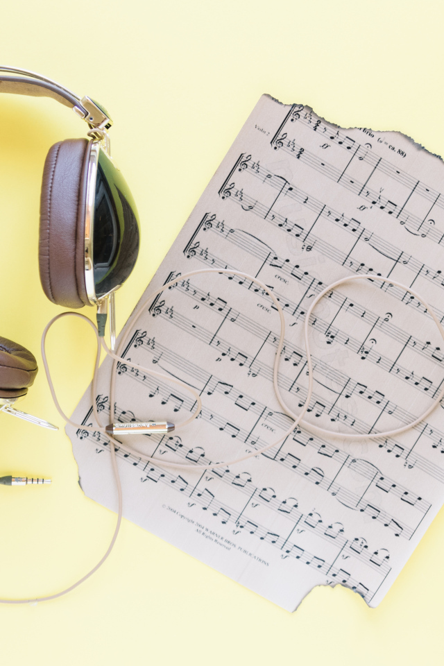 Старые ноты и наушники на желтом фоне
