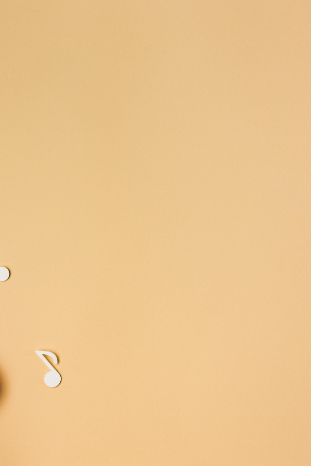 Маленькая гитара с нотами на бежевом фоне