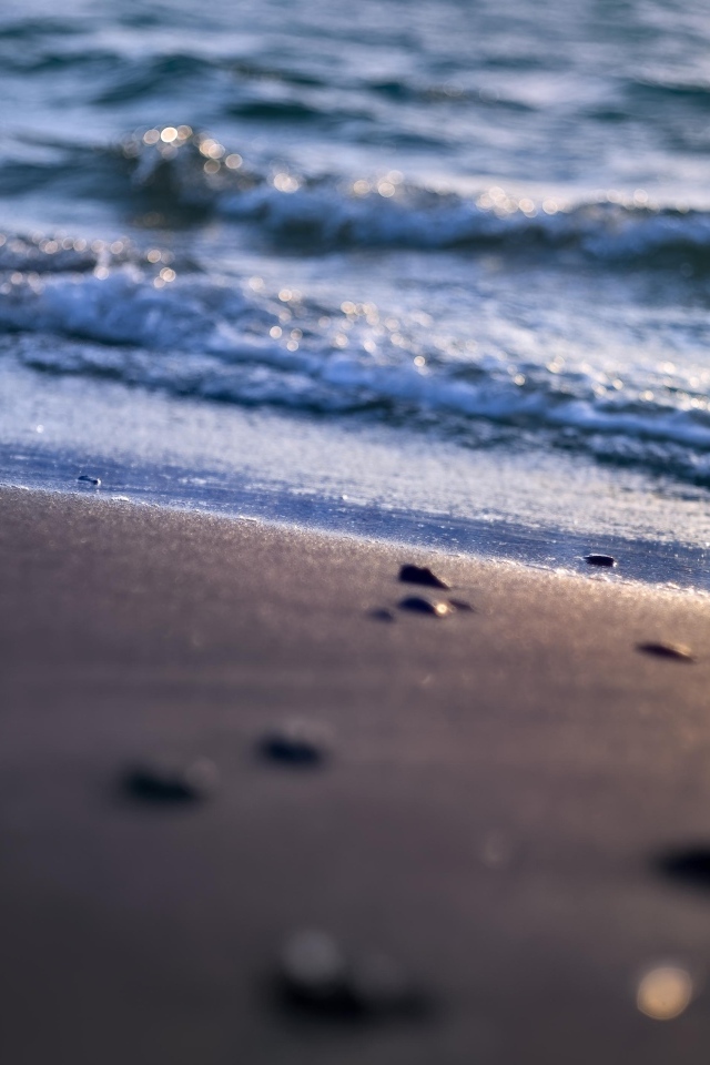 Мокрый морской песок омывает вода