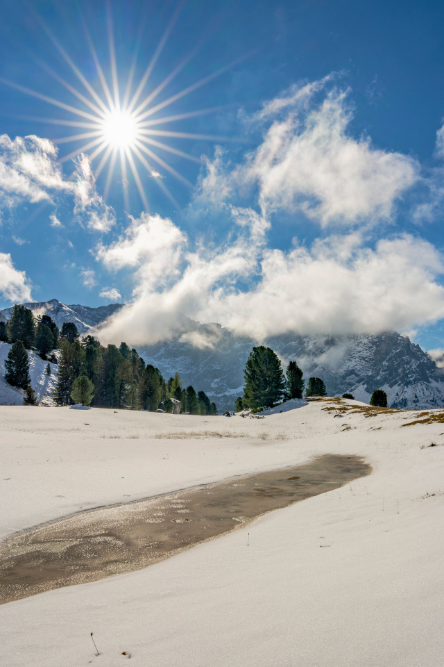 Яркое солнце над горами у заледеневшего озера