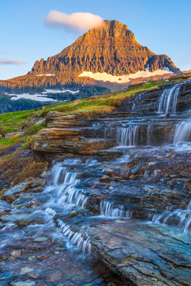 Водопад стекает по камням у высокой горы