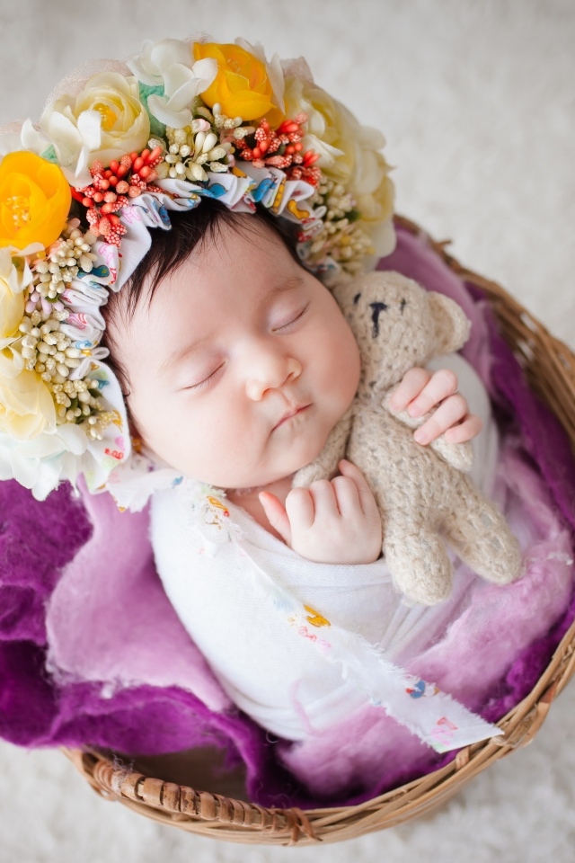 Младенец с венком на голове спит в корзине