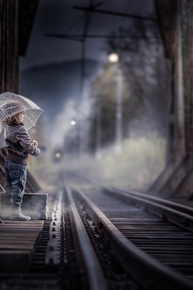 Ребенок под зонтом у железной дороги