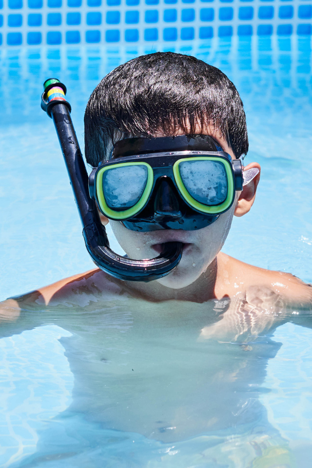 Мальчик в маске сидит в плавательном бассейне