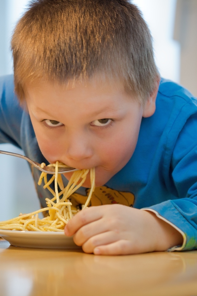 Маленький мальчик ест макароны