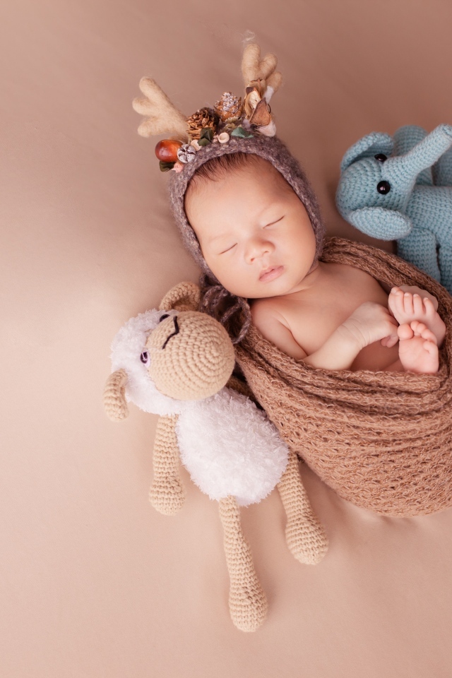 Маленький ребенок в костюме оленя с игрушкой