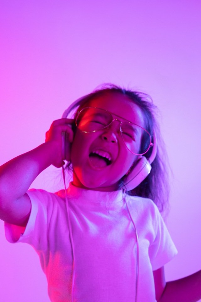 Маленькая девочка в наушниках с телефоном слушает музыку