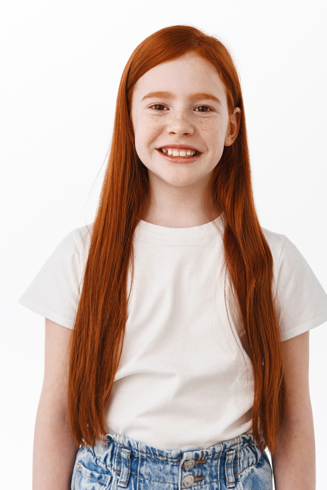 Улыбающаяся рыжеволосая девочка на белом фоне