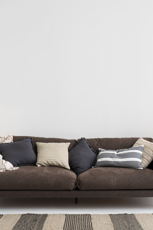 Коричневый диван у серой стены с лампой