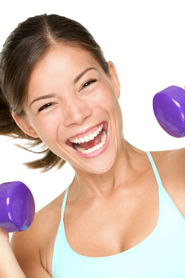 Веселая спортивная девушка с гантелями в руках