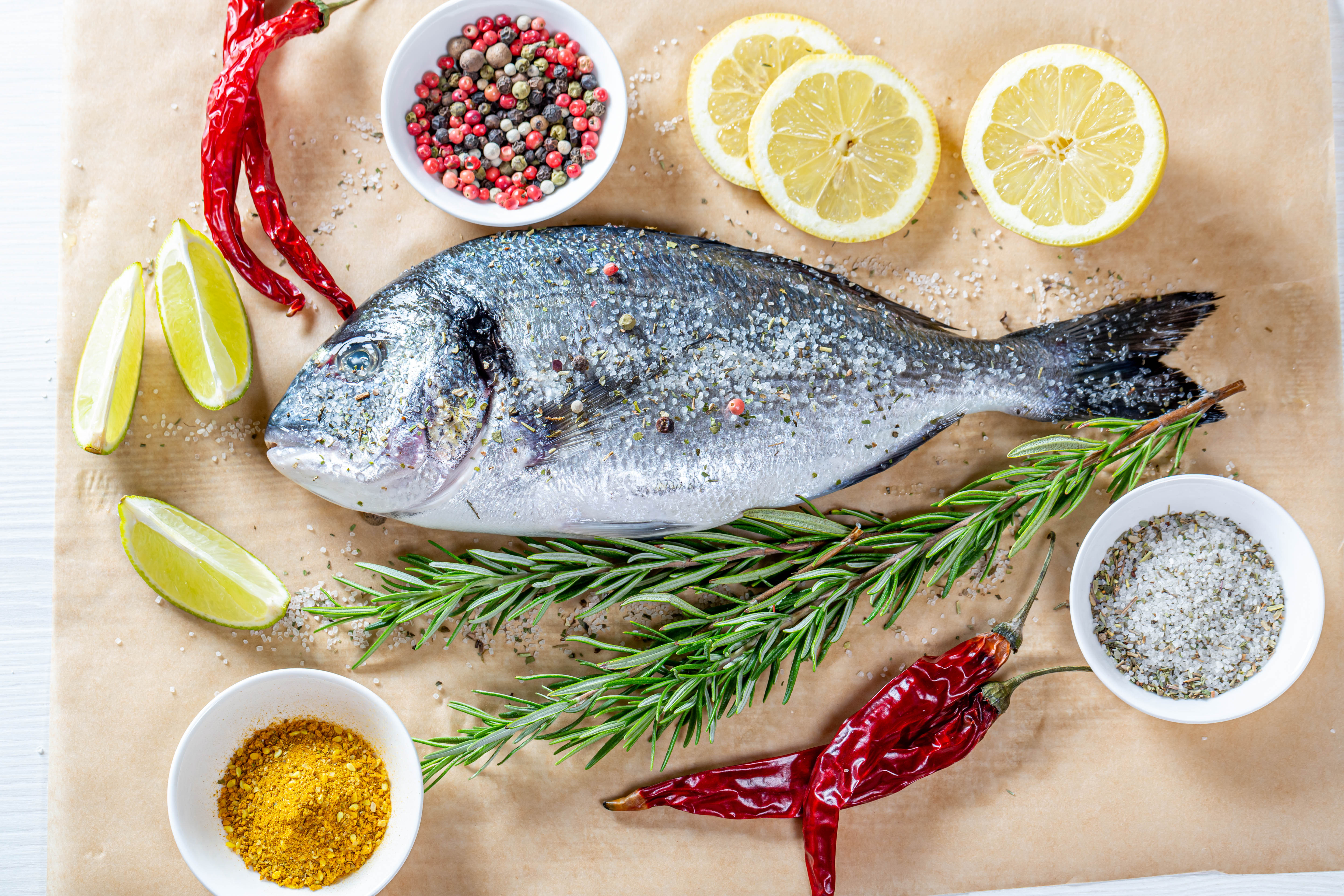 Zastaki.com - Свежая рыба на столе со специями, лимоном, розмарином и красным перцем