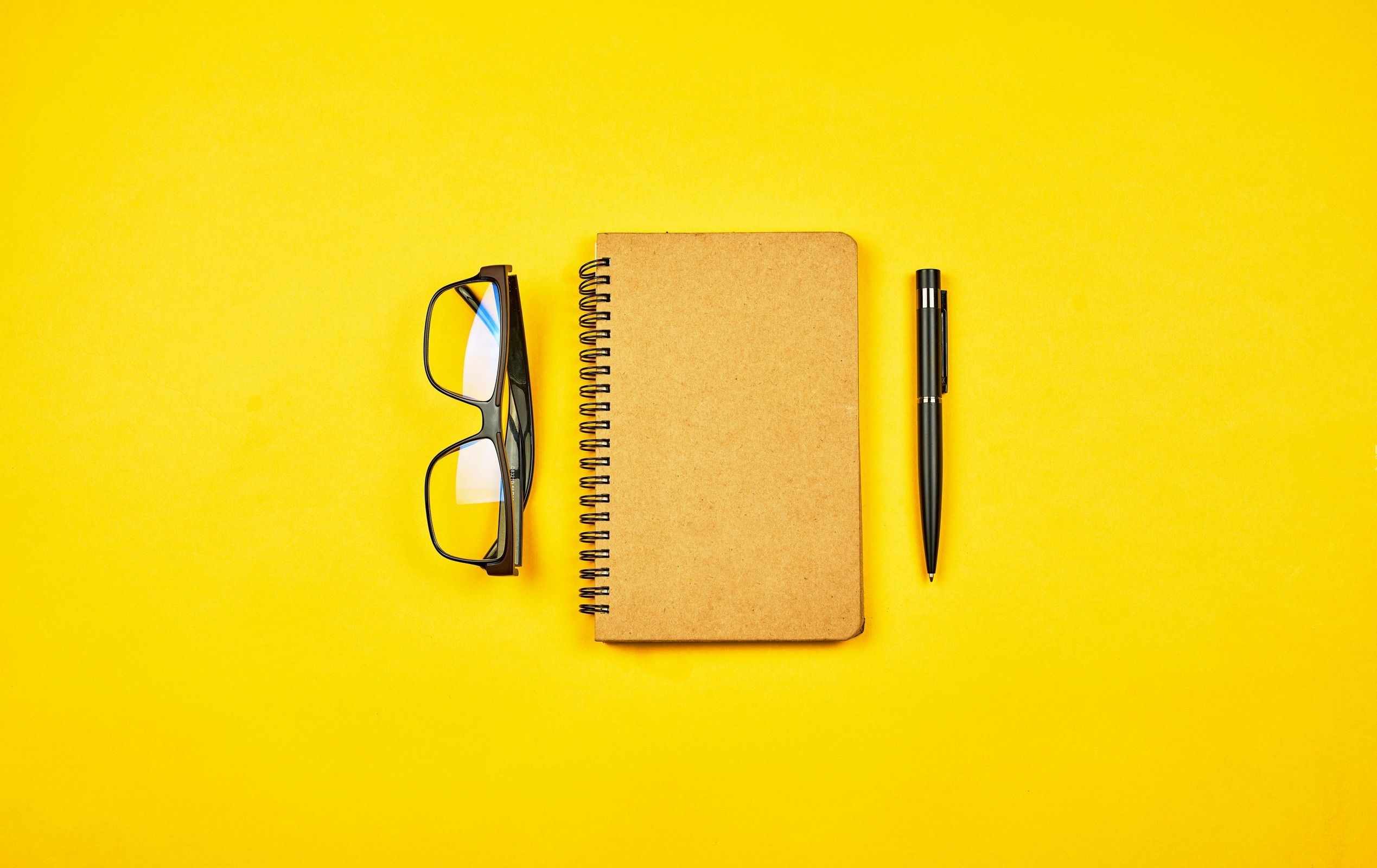 Zastaki.com - Блокнот, очки и ручка на желтом фоне