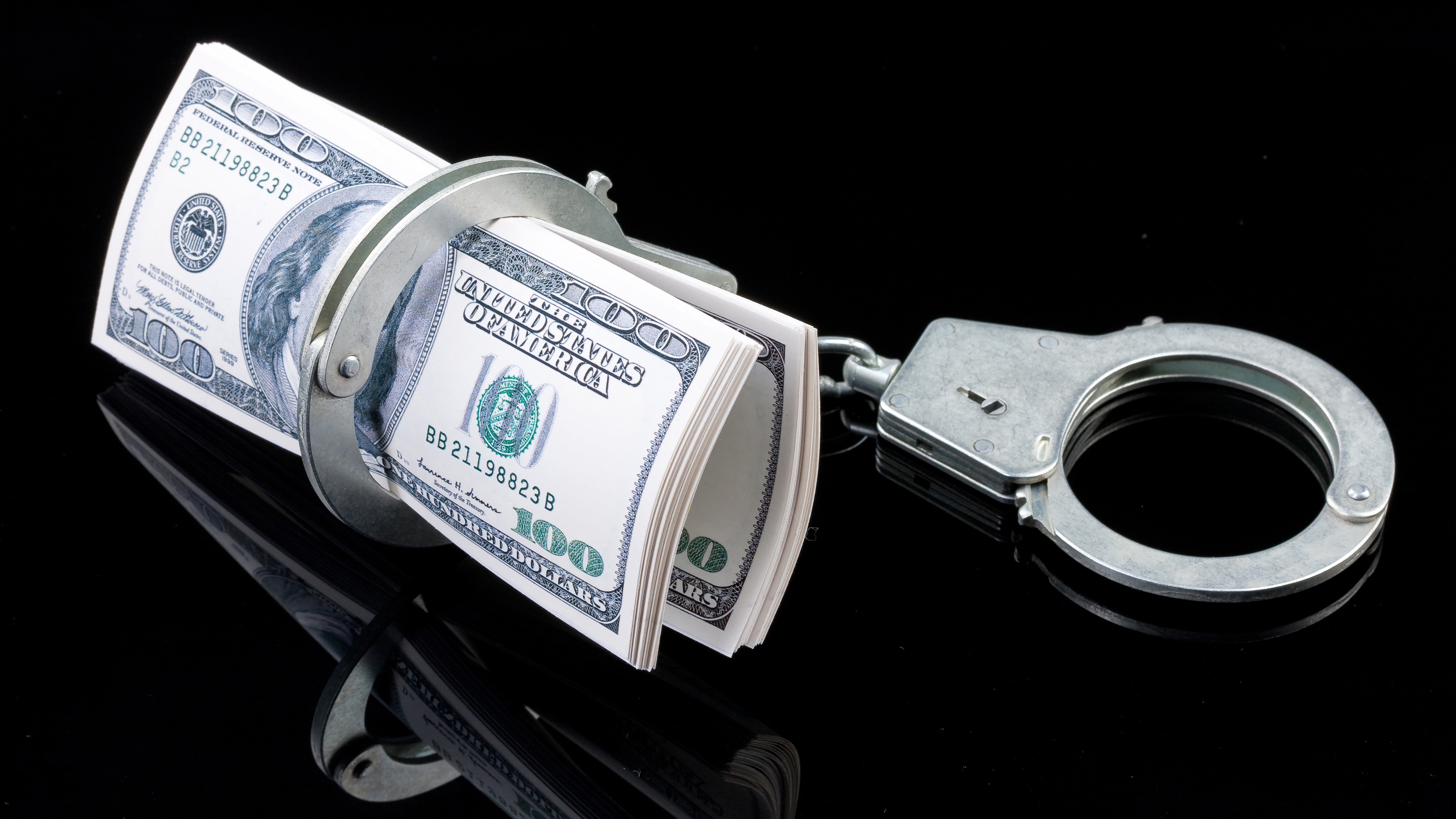 Zastaki.com - Пачка долларов с наручниками на черном фоне