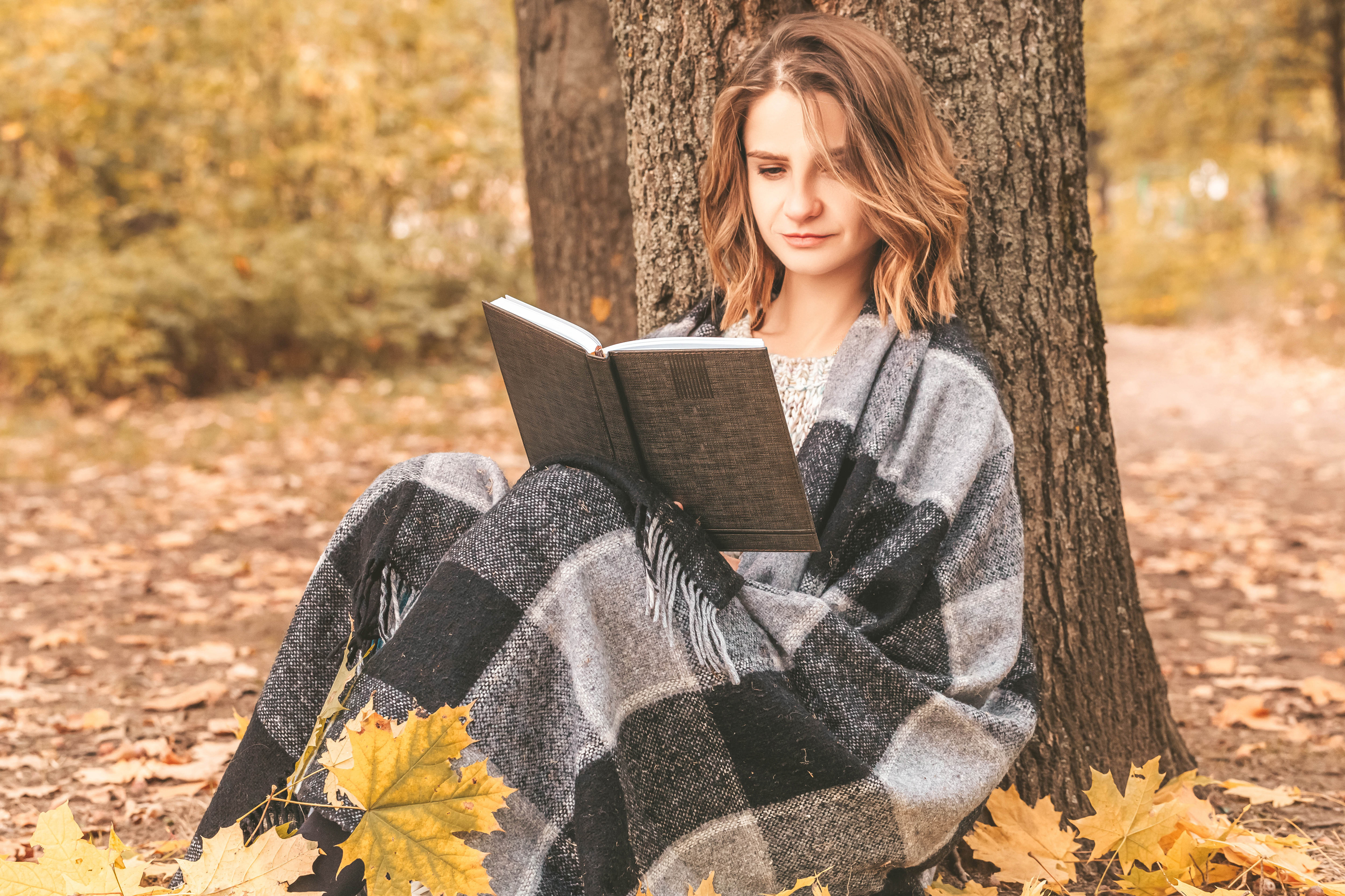 Сидящая женщина с книгой. Девушка в пледе. Девушка осень. Осенний плед. Фотосессия с книгой осенью.