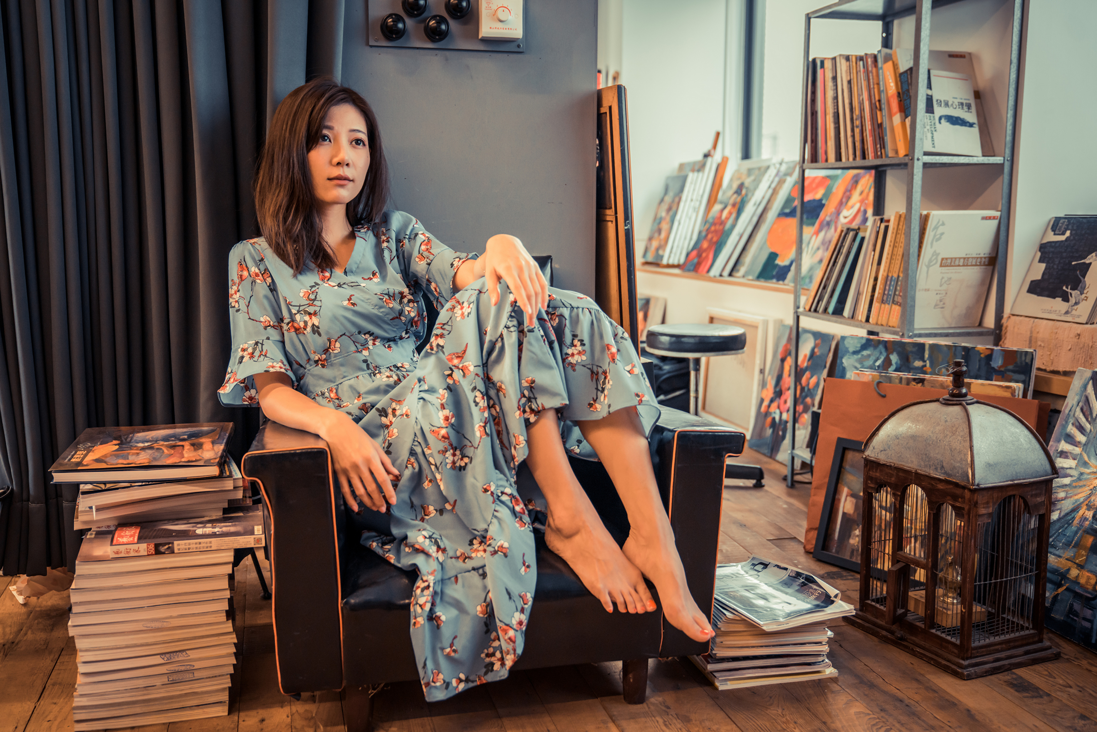 Zastaki.com - Девушка азиатка сидит в большом кресле в комнате с книгами