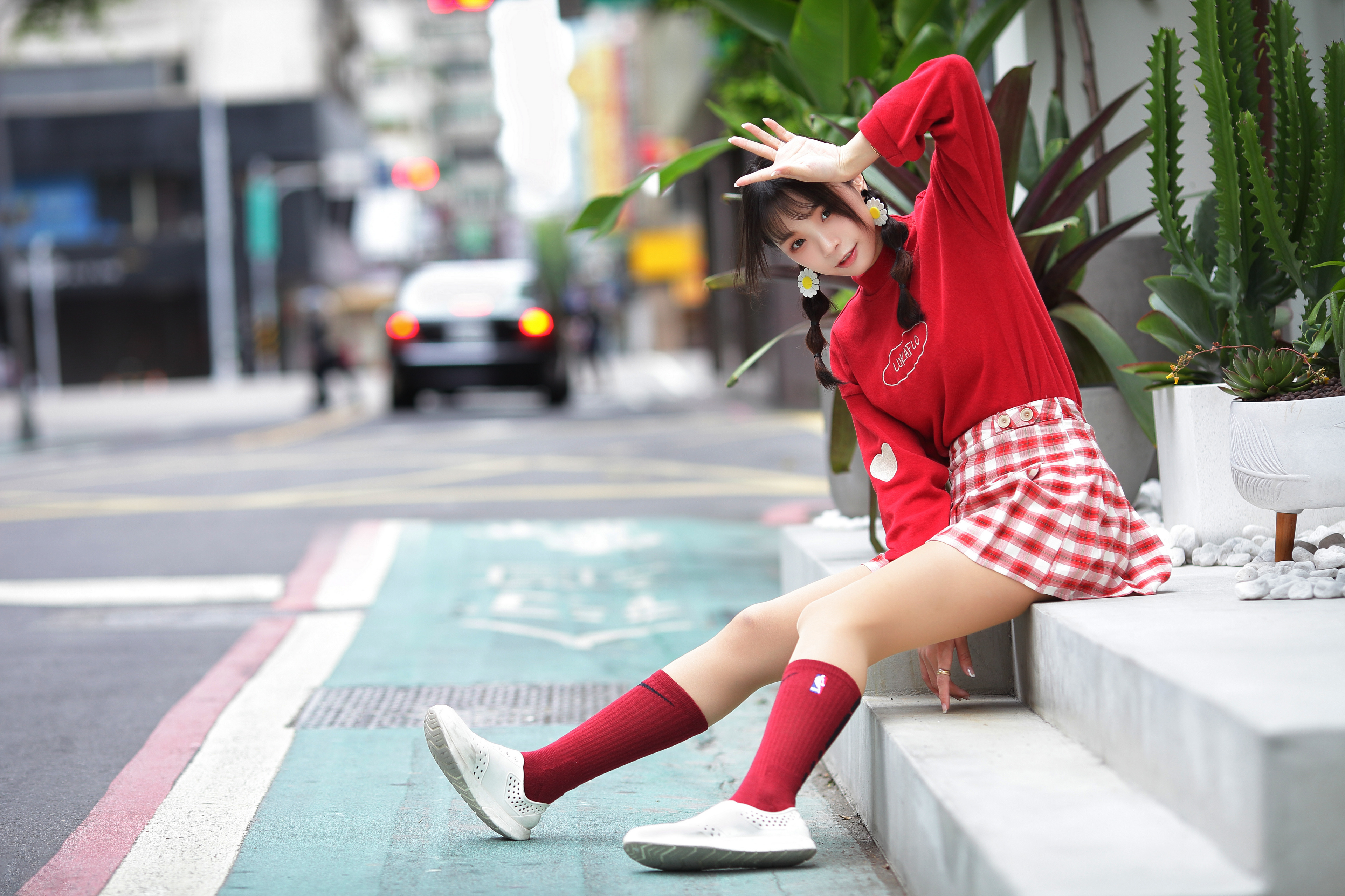 Zastaki.com - Веселая девушка азиатка в красном костюме сидит на ступеньках 